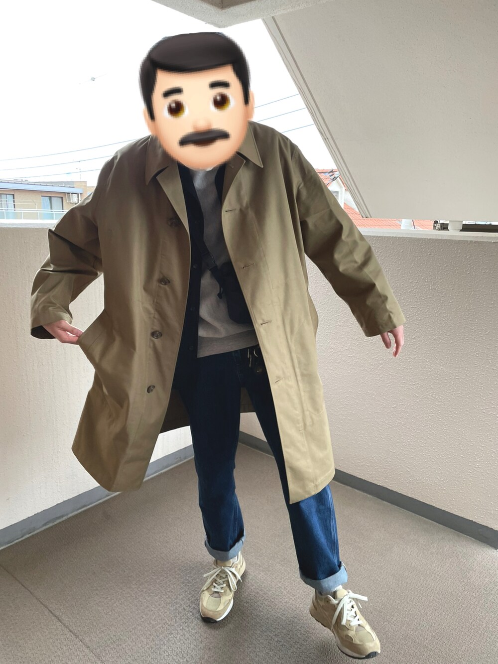 ベージュ系のステンカラーコート、ブルー系のデニムパンツ、ベージュ系のスニーカーを着用したメンズの冬コーディネートの2枚目の写真