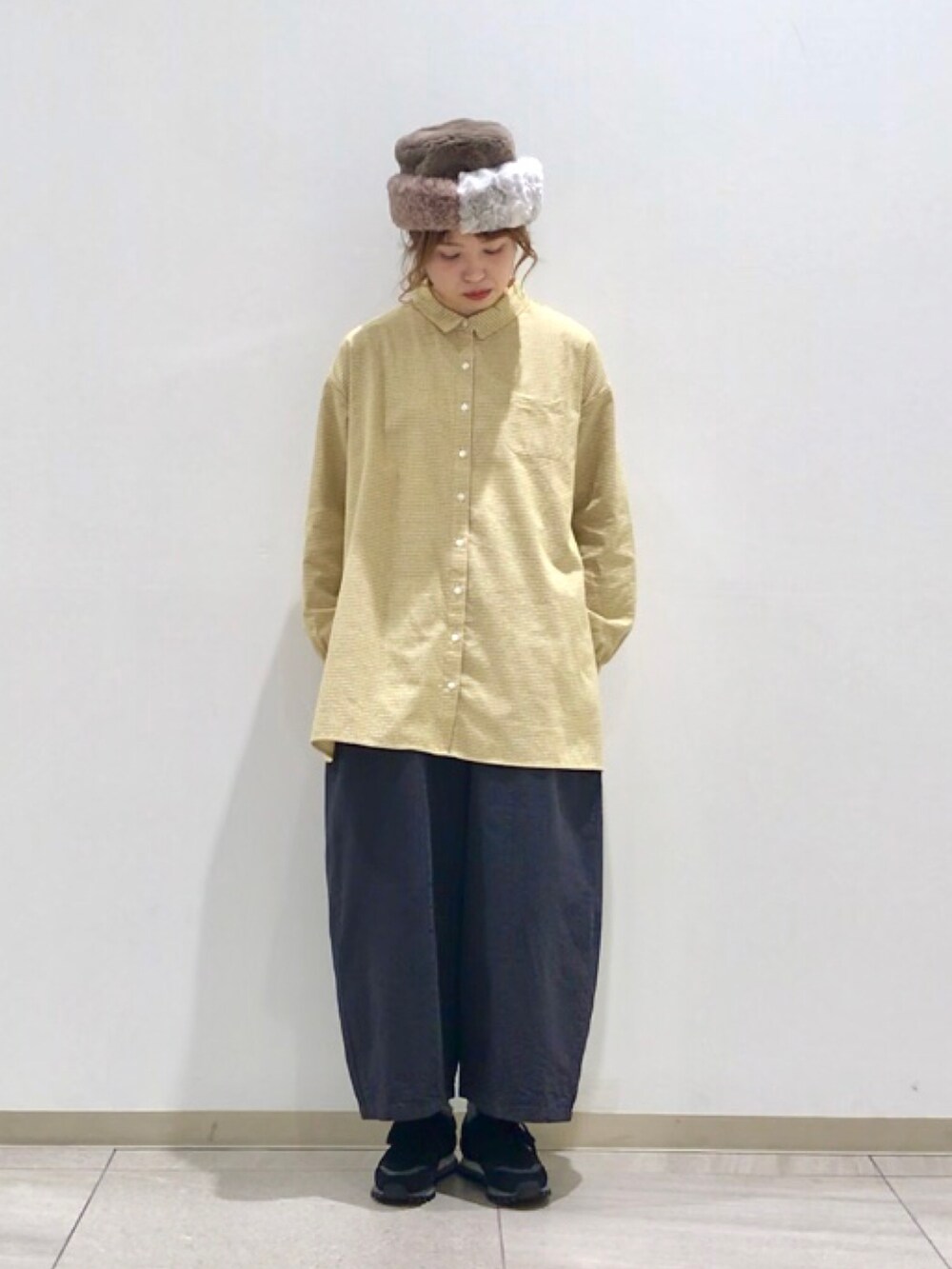 イエロー系のチュニック、グレー系のその他パンツを着用したレディースの冬コーディネートの3枚目の写真