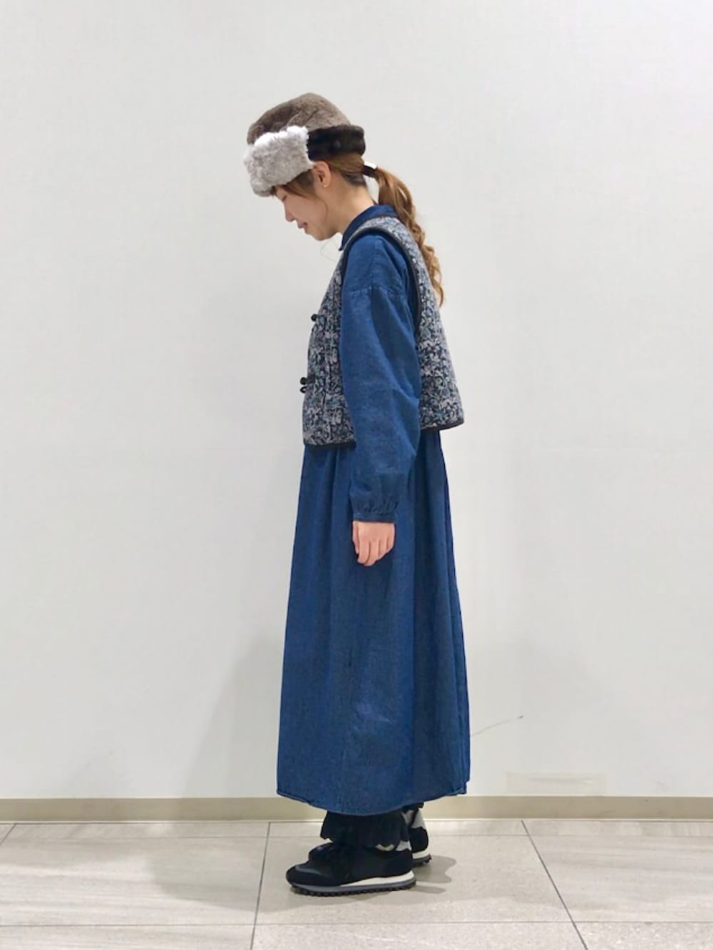 グレー系のベスト、ブルー系のワンピース、ブラック系のその他パンツを着用したレディースの冬コーディネートの2枚目の写真