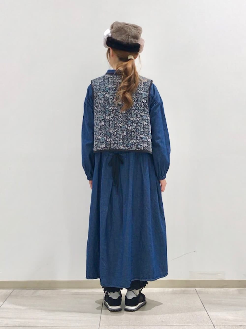 グレー系のベスト、ブルー系のワンピース、ブラック系のその他パンツを着用したレディースの冬コーディネートの3枚目の写真