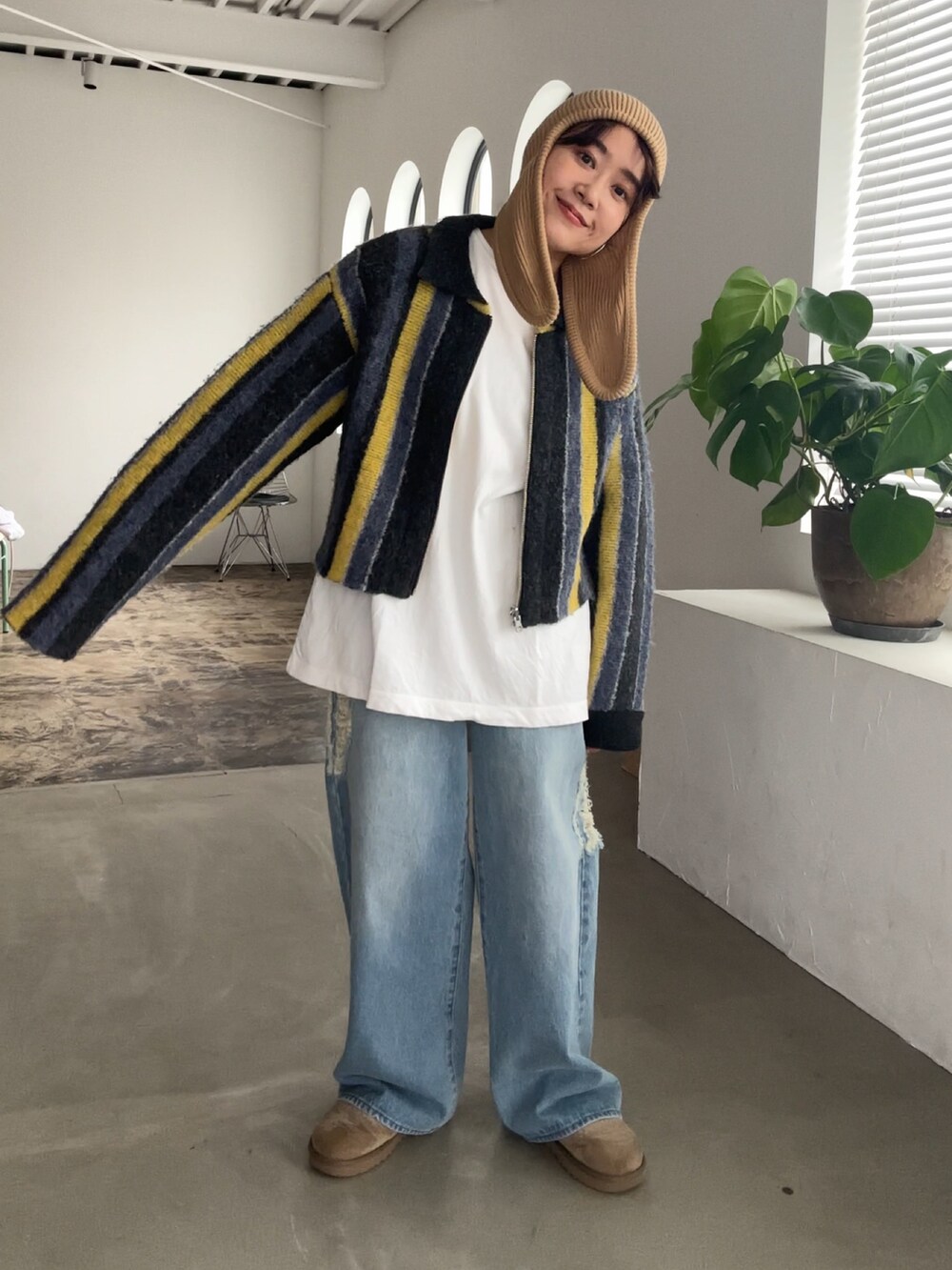 グレー系のカーディガン/ボレロ、ベージュ系のブーツ、ブルー系のデニムパンツを着用したレディースの秋コーディネートの2枚目の写真