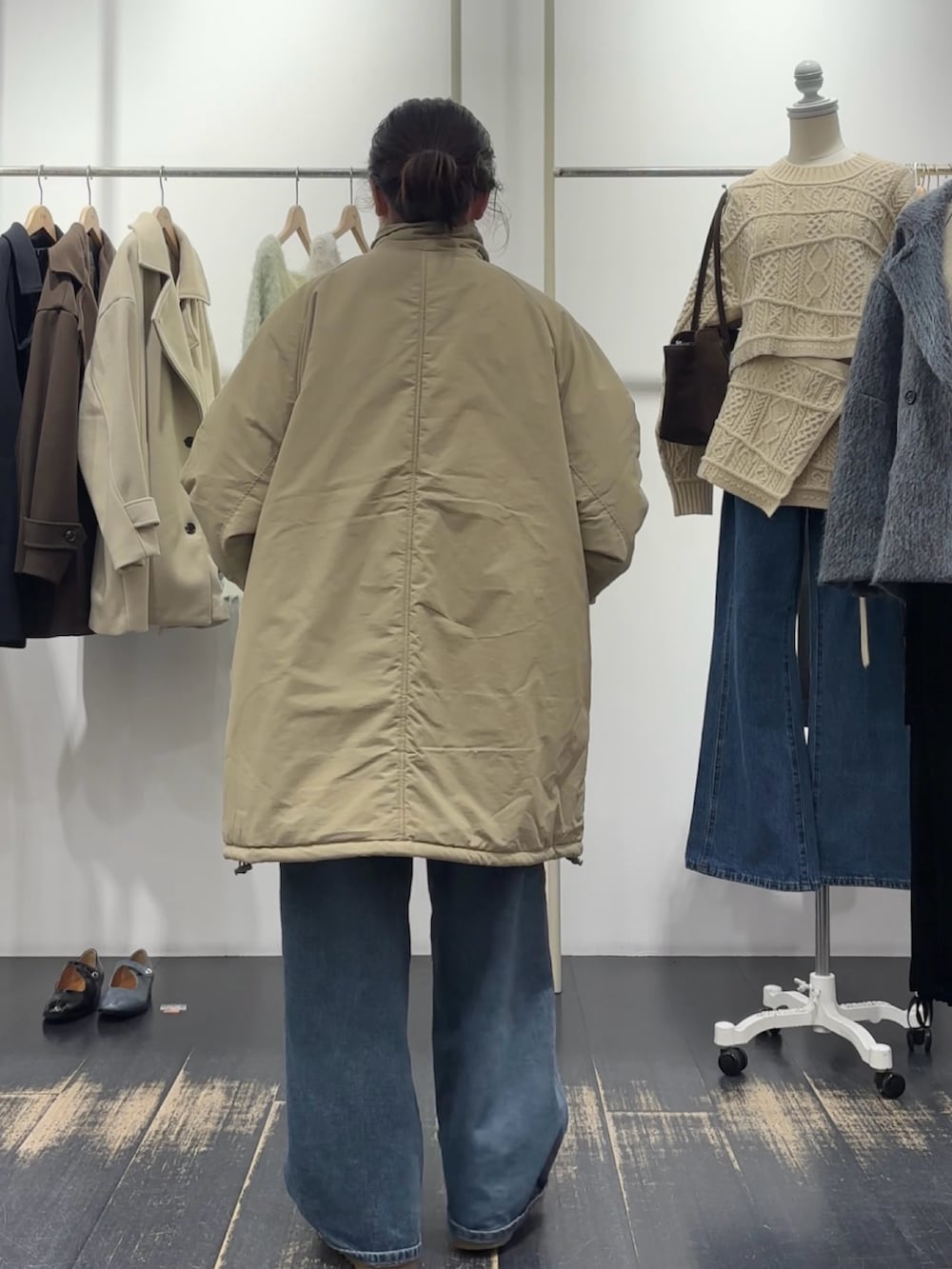 グリーン系のダウンジャケット/コート、ブラウン系のハンドバッグ、ホワイト系のニット/セーターを着用したレディースの冬コーディネートの3枚目の写真