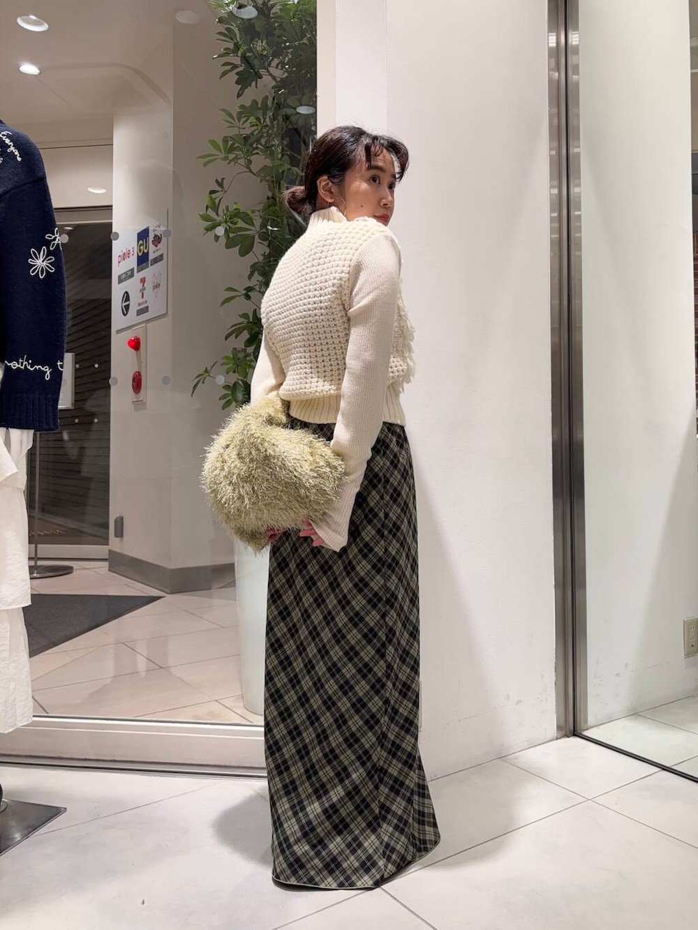 ブラック系のブーツ、ベージュ系のトートバッグ、グリーン系のスカートを着用したレディースの冬コーディネートの2枚目の写真