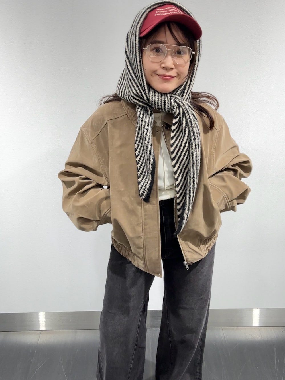 ブラック系のデニムパンツ、ベージュ系のブルゾン、ホワイト系のTシャツ/カットソーを着用したレディースの秋コーディネートの3枚目の写真