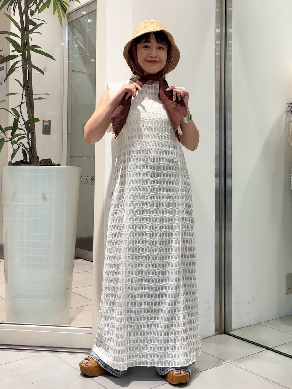 ホワイト系のワンピース、ブルー系のデニムパンツ、イエロー系のサンダルを着用したレディースの夏コーディネートの2枚目の写真