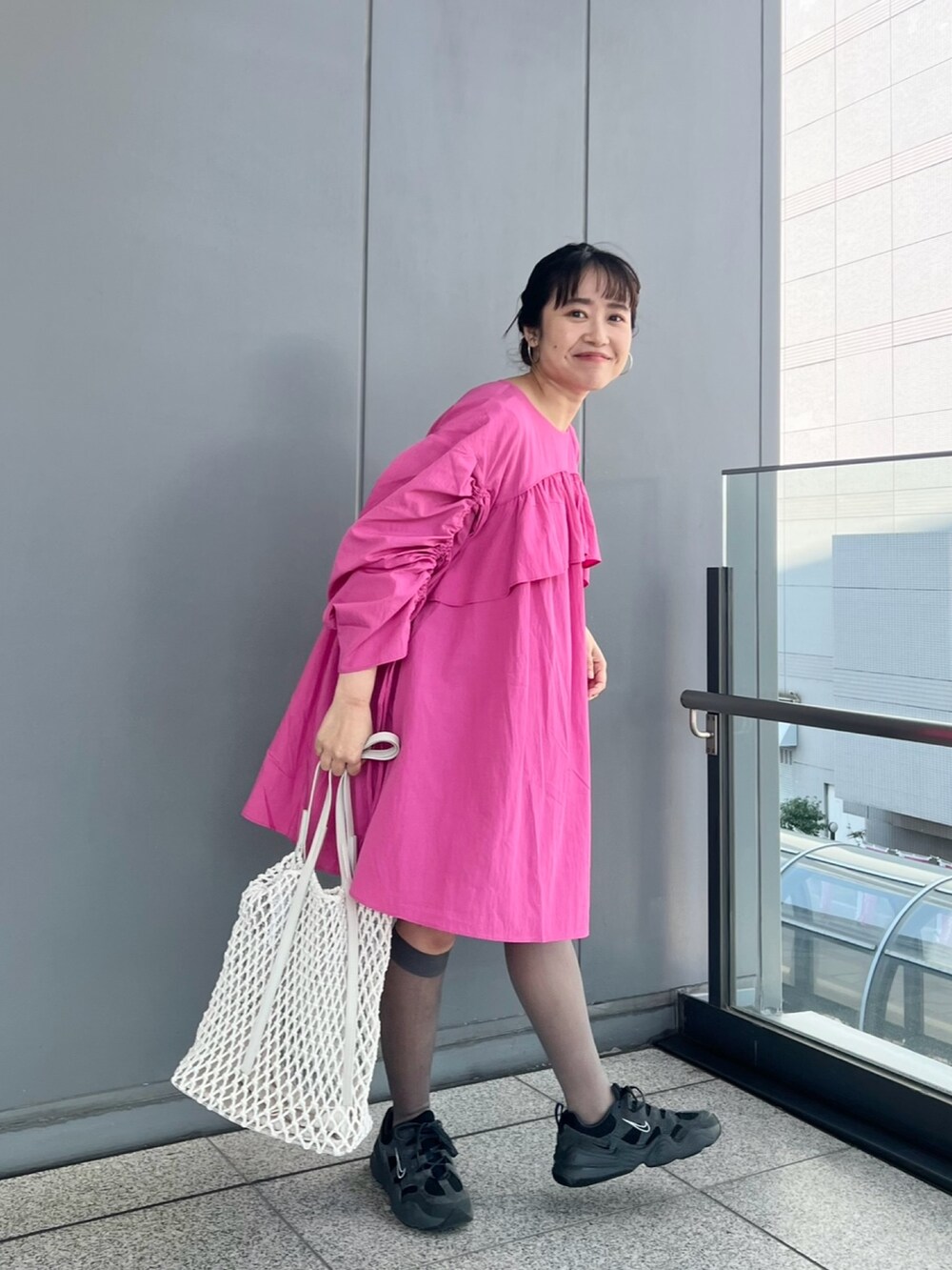 ピンク系のワンピース、ホワイト系のハンドバッグ、グレー系のシューズを着用したレディースの春コーディネートの2枚目の写真