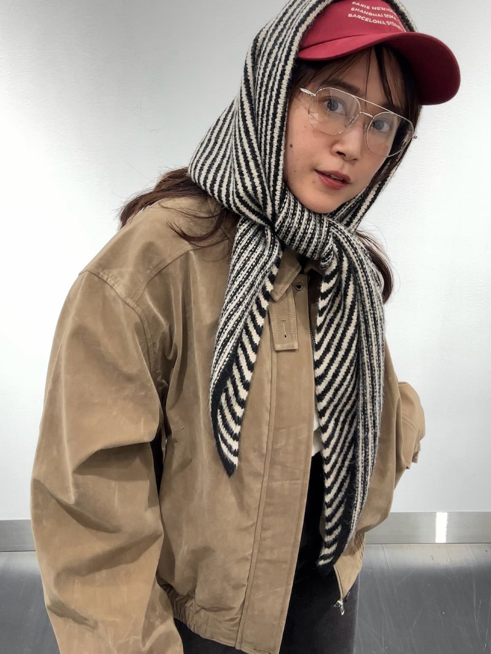 ブラック系のデニムパンツ、ベージュ系のブルゾン、ホワイト系のTシャツ/カットソーを着用したレディースの秋コーディネートの2枚目の写真