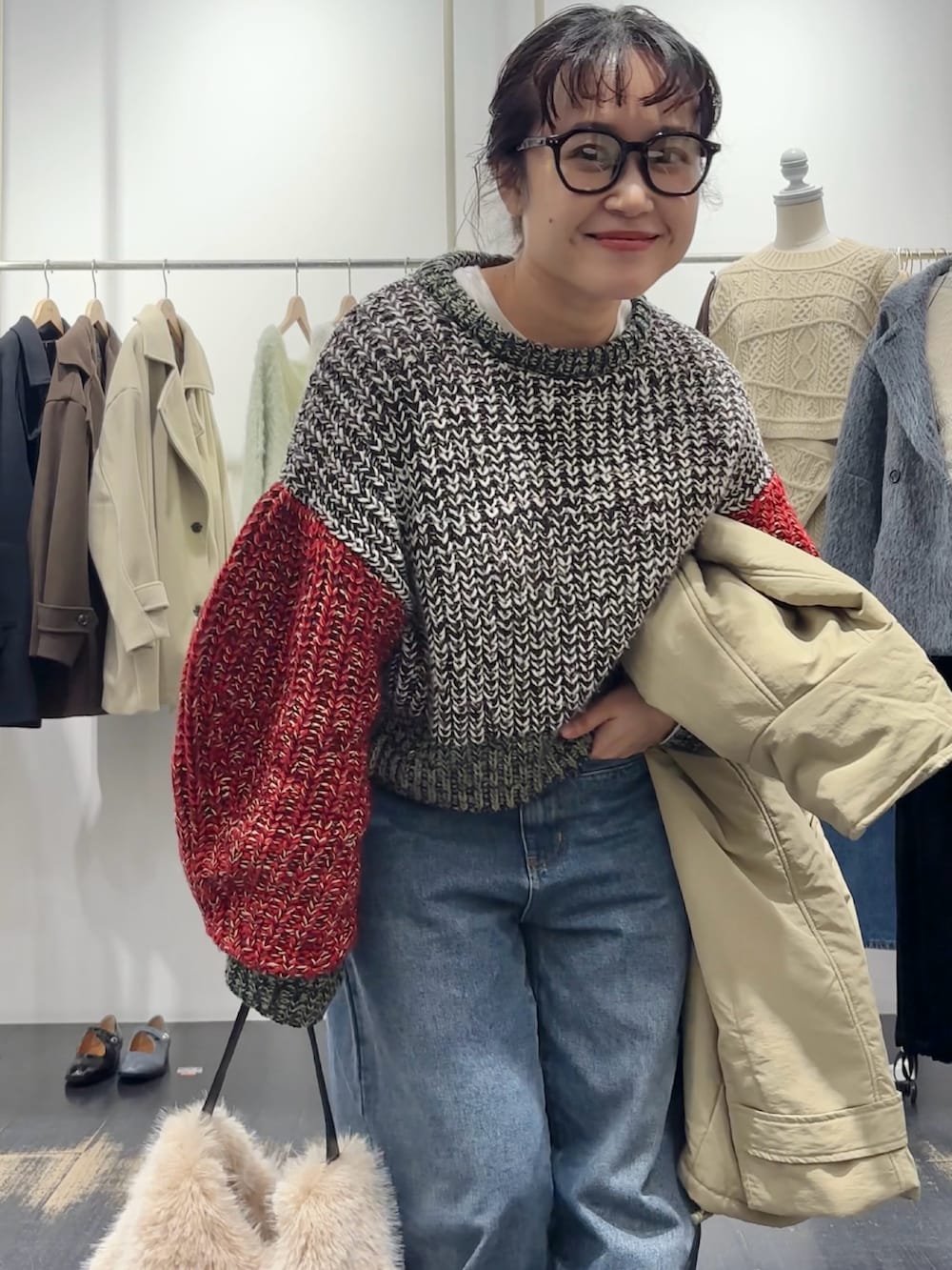 グリーン系のダウンジャケット/コート、ブラウン系のハンドバッグ、ホワイト系のニット/セーターを着用したレディースの冬コーディネートの5枚目の写真