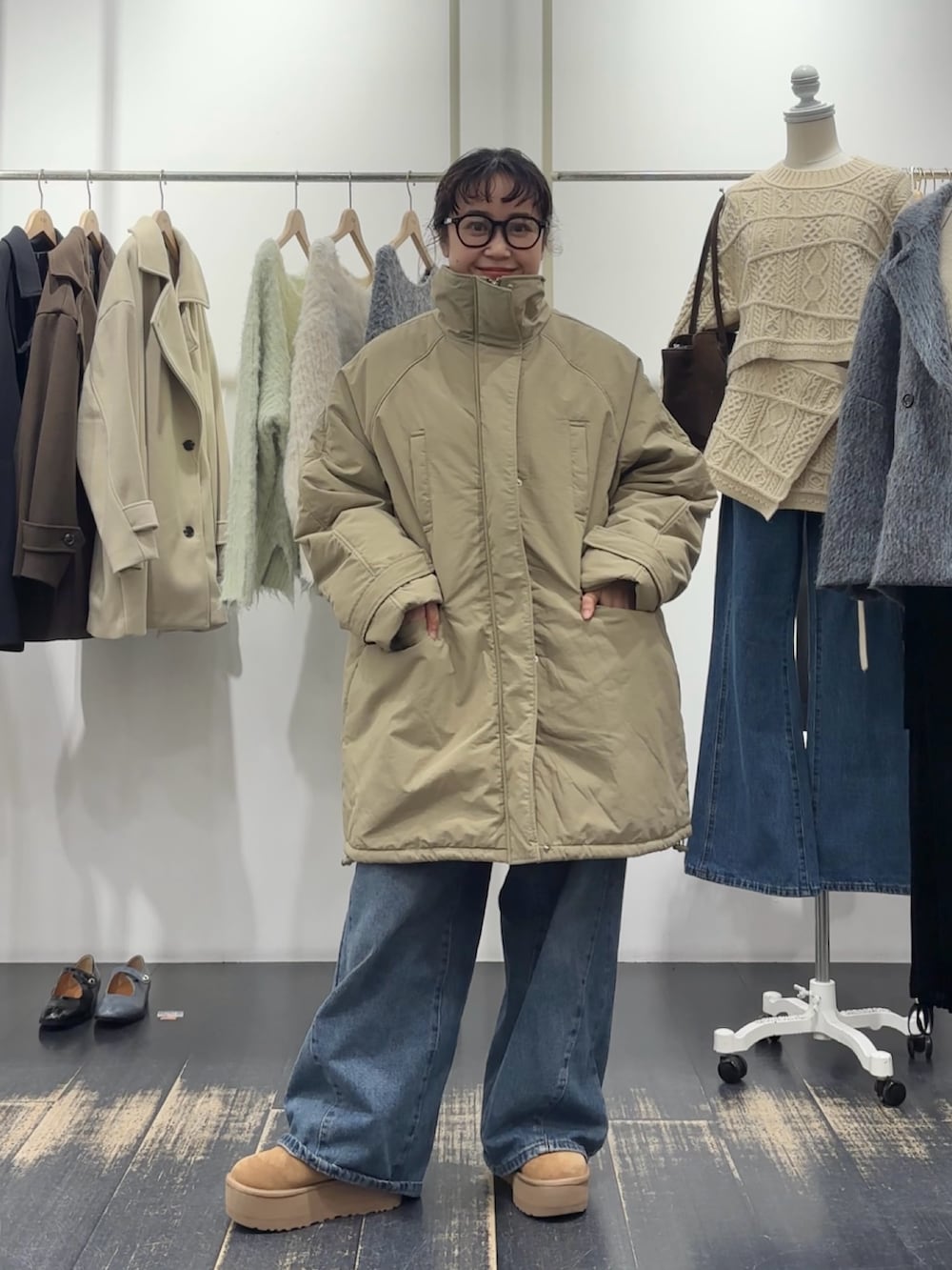 グリーン系のダウンジャケット/コート、ブラウン系のハンドバッグ、ホワイト系のニット/セーターを着用したレディースの冬コーディネートの2枚目の写真