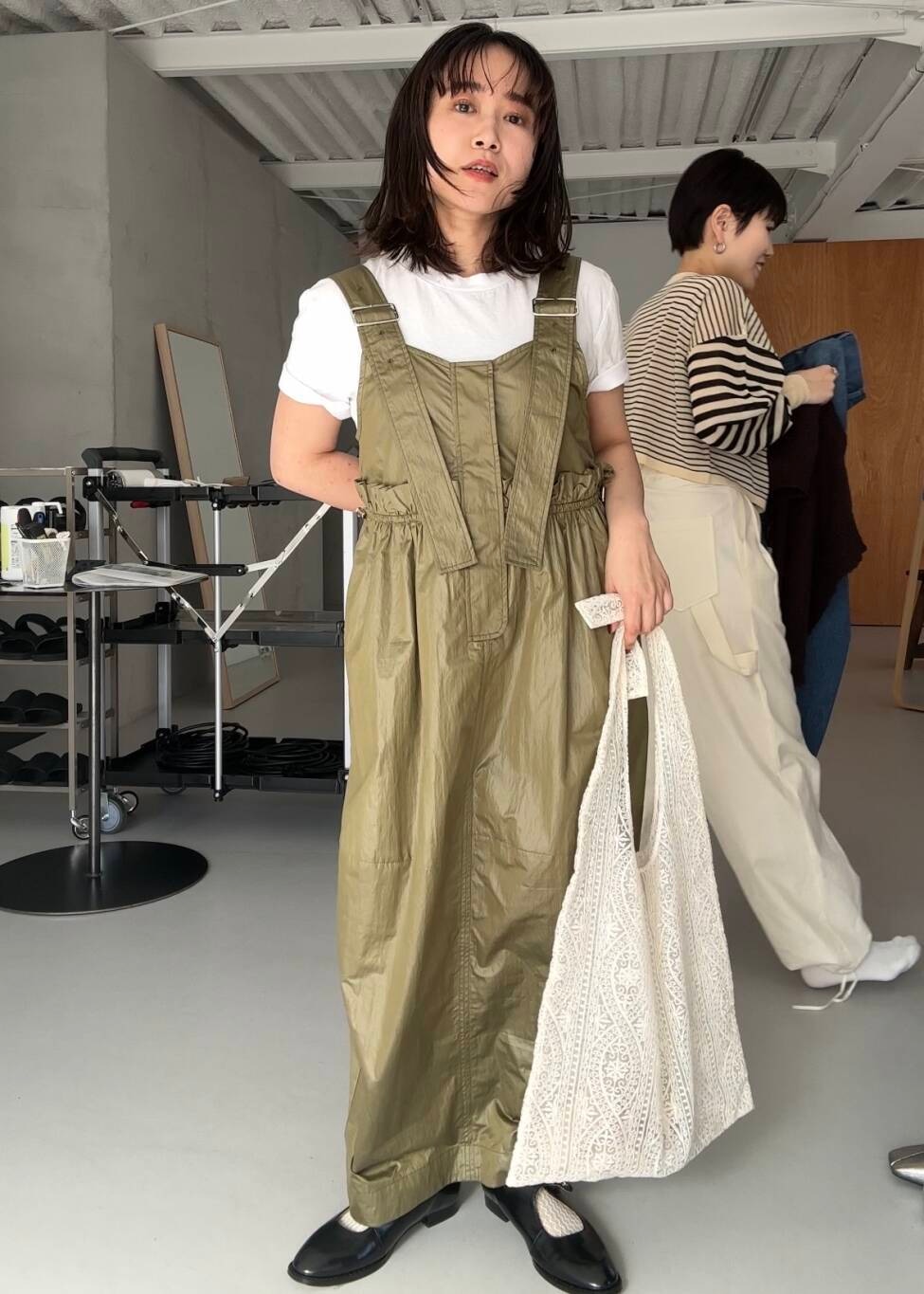 ブラック系のローファー、ホワイト系のショルダーバッグ、グリーン系のワンピースを着用したレディースの冬コーディネートの2枚目の写真