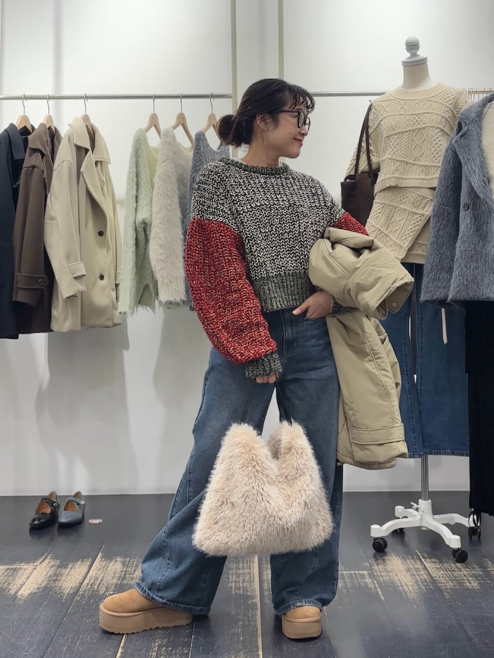 グリーン系のダウンジャケット/コート、ブラウン系のハンドバッグ、ホワイト系のニット/セーターを着用したレディースの冬コーディネートの4枚目の写真