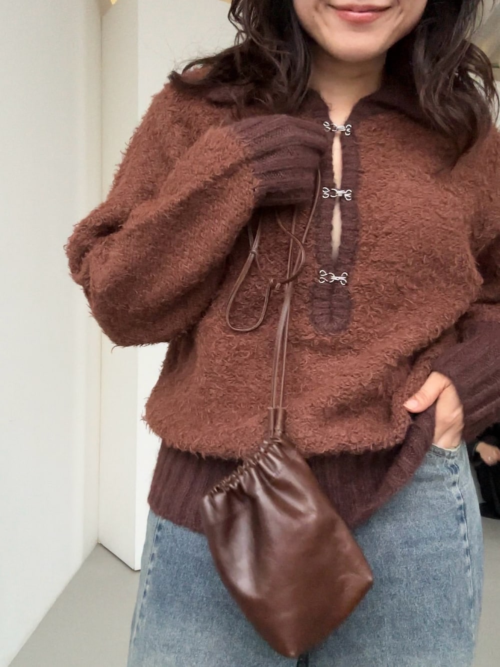 ブラウン系のニット/セーター、ブラウン系のニット/セーター、ブルー系のデニムパンツを着用したレディースの秋コーディネートの3枚目の写真