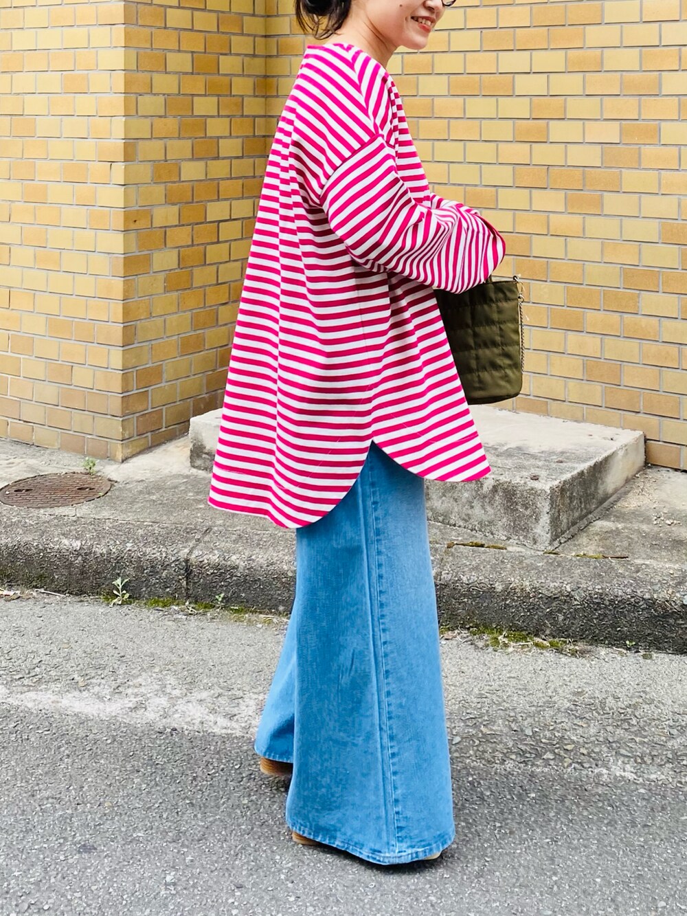 ピンク系のTシャツ/カットソー、ブルー系のデニムパンツ、ホワイト系のサンダルを着用したレディースの春コーディネートの2枚目の写真