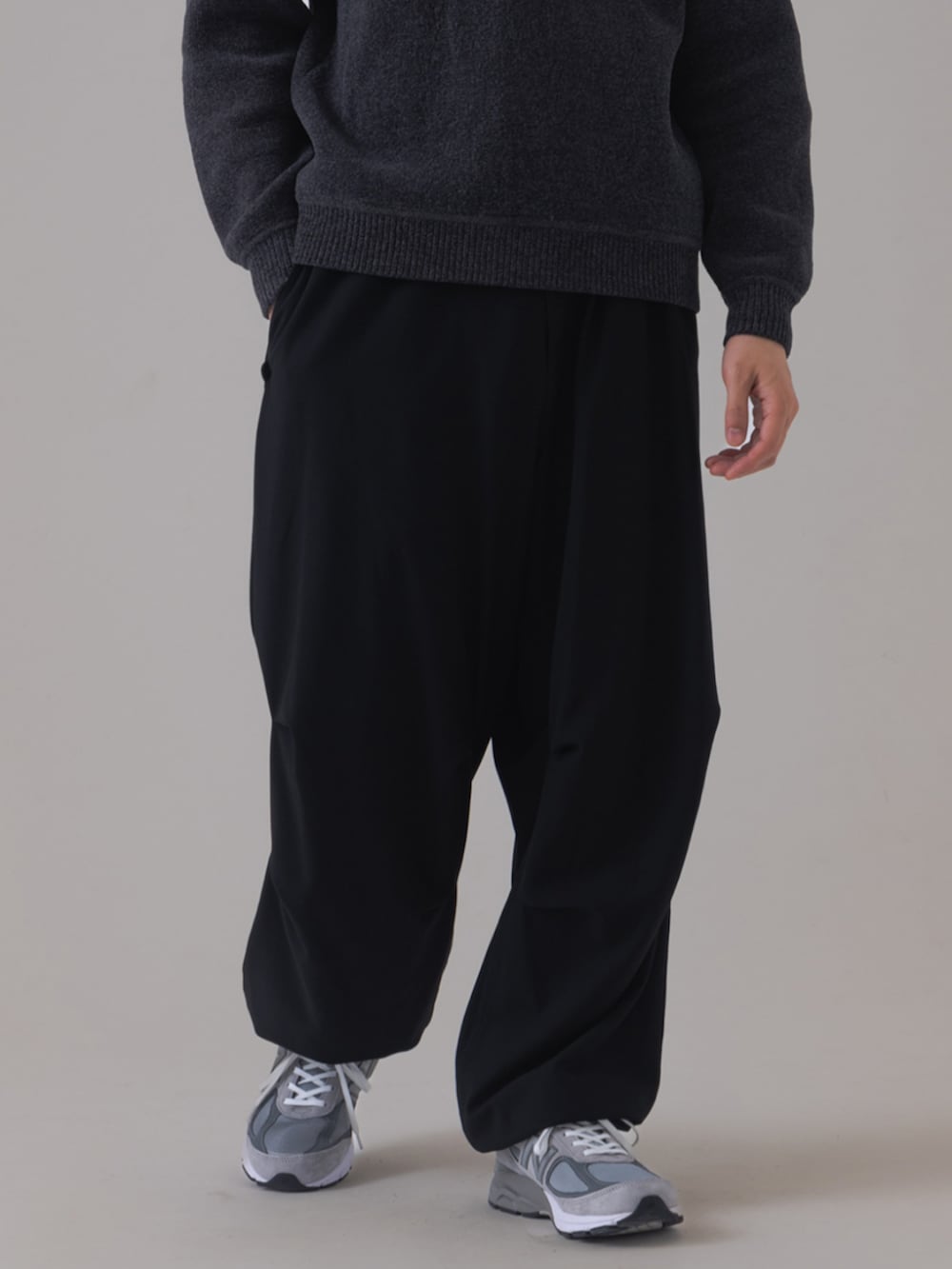 グレー系のスニーカー、ブラック系のスラックス、グレー系のニット/セーターを着用したメンズの秋コーディネートの3枚目の写真