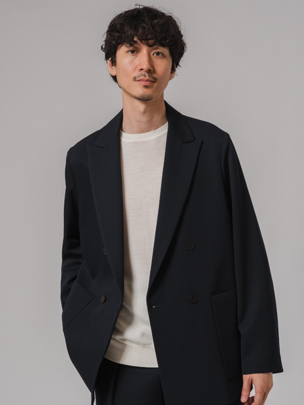 ホワイト系のスニーカー、ホワイト系のニット/セーター、ブルー系のスラックスを着用したメンズの秋コーディネートの2枚目の写真