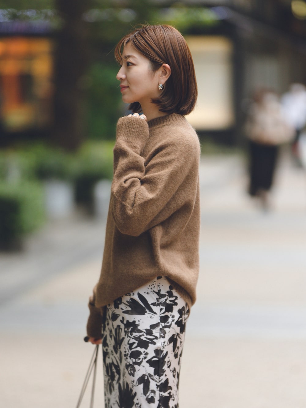 ベージュ系のスカート、ブラウン系のニット/セーター、ブラウン系のバッグを着用したレディースの秋コーディネートの2枚目の写真