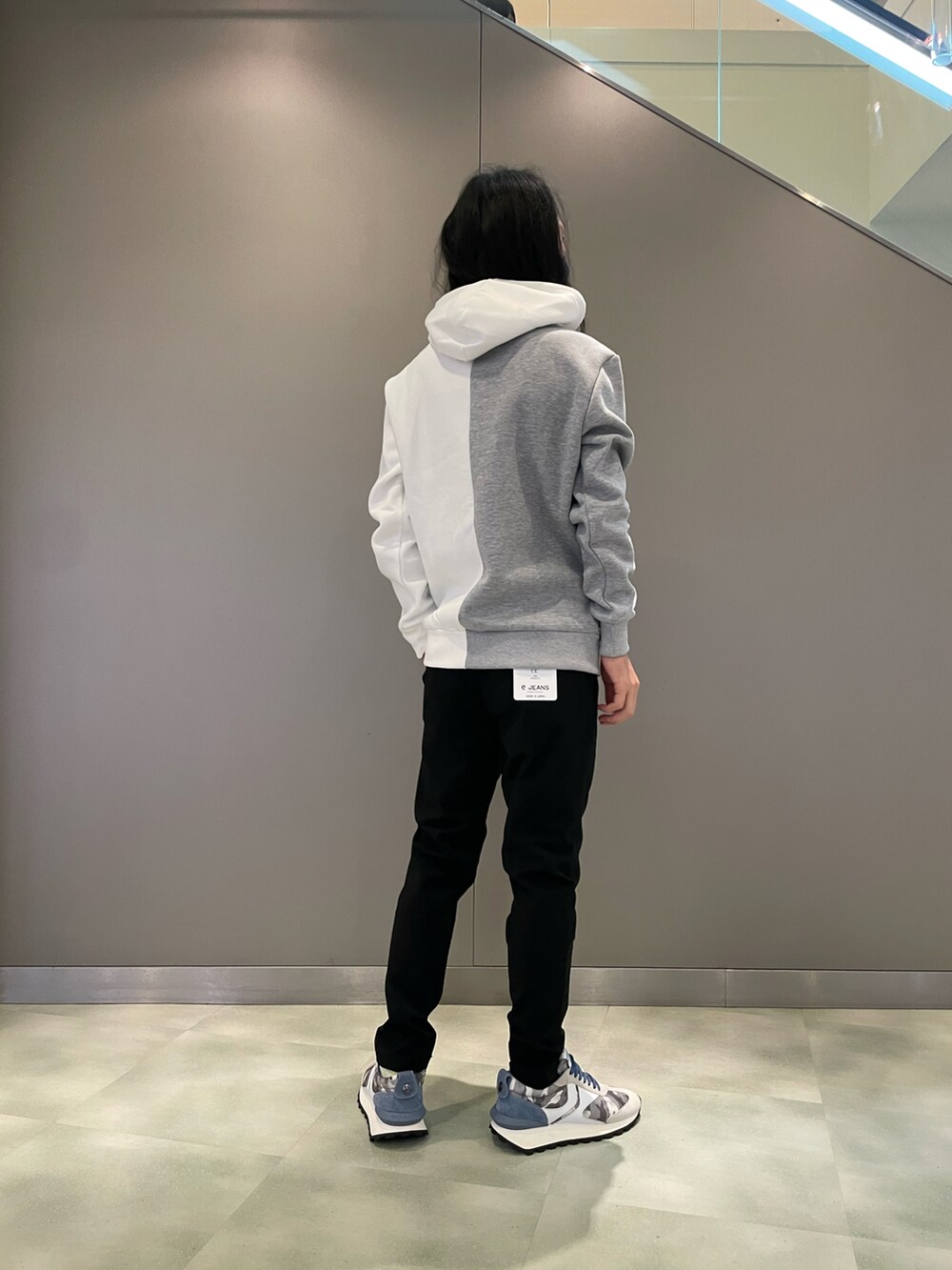 ホワイト系のパーカー、ブラック系のスラックス、グレー系のスニーカーを着用したメンズの夏コーディネートの3枚目の写真