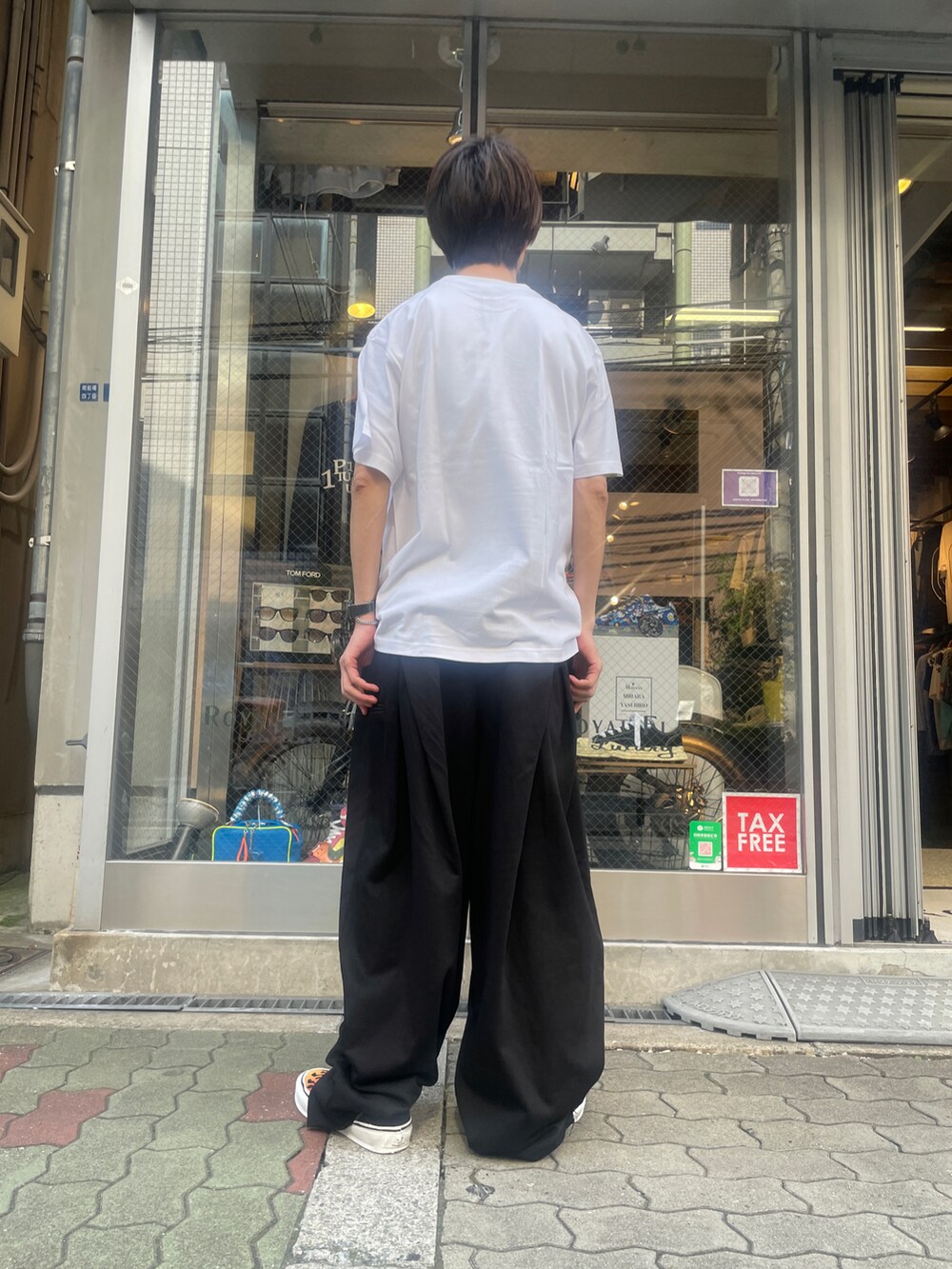 ホワイト系のTシャツ/カットソー、ブラック系のパンツ、ブラック系のスニーカーを着用したメンズの夏コーディネートの3枚目の写真
