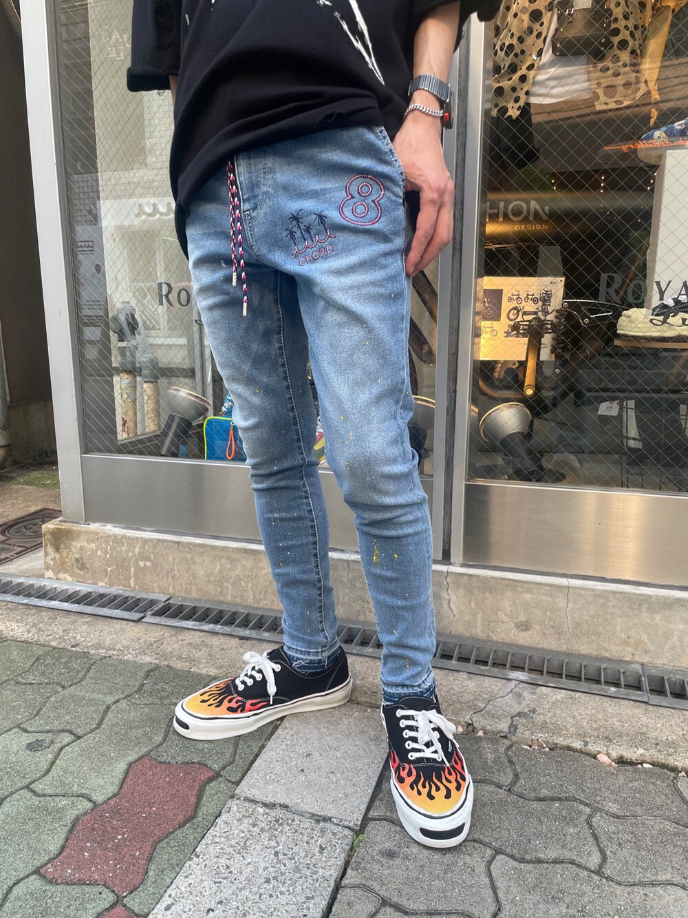 ブラック系のニット/セーター、ブラック系のスニーカー、ブルー系のデニムパンツを着用したメンズの夏コーディネートの5枚目の写真