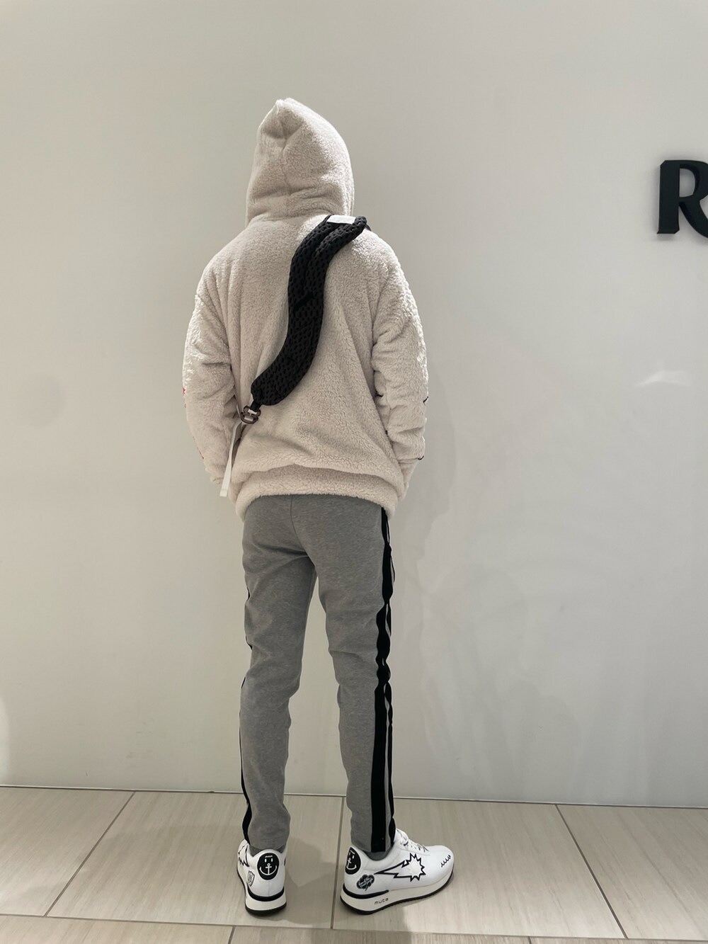 ホワイト系のトップス、ブラック系のショルダーバッグ、ホワイト系のスニーカーを着用したメンズの冬コーディネートの3枚目の写真