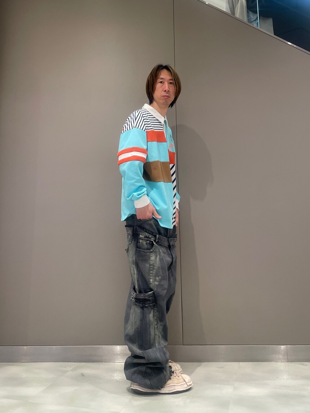 ブラック系のデニムパンツ、ブルー系のポロシャツ、ホワイト系のスニーカーを着用したメンズの春コーディネートの2枚目の写真