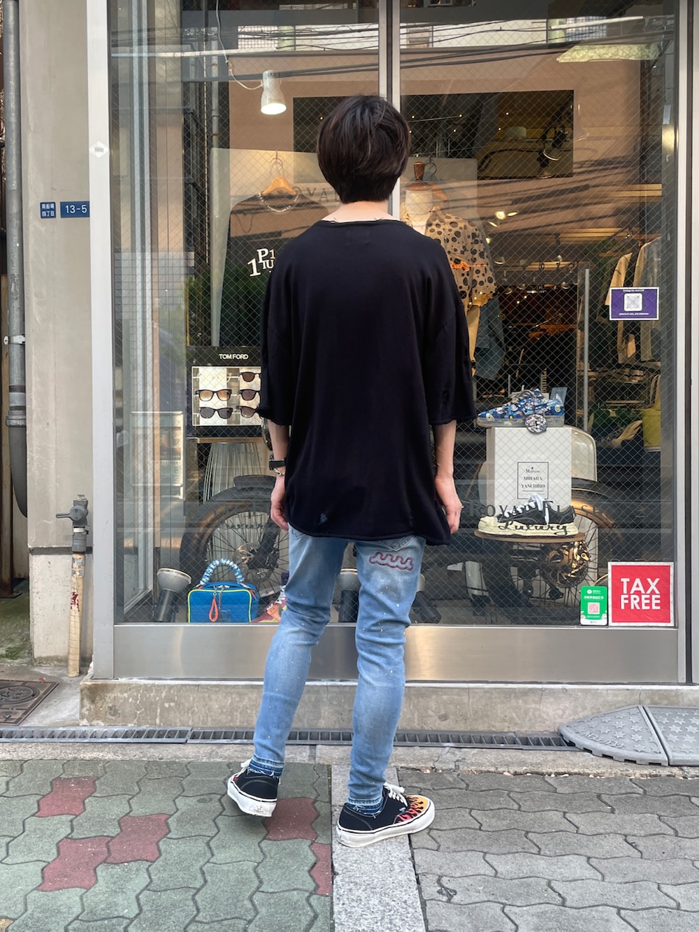 ブラック系のニット/セーター、ブラック系のスニーカー、ブルー系のデニムパンツを着用したメンズの夏コーディネートの3枚目の写真