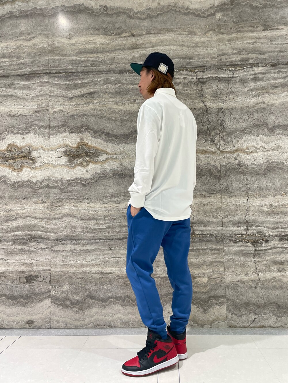 ホワイト系のポロシャツ、ブルー系のスウェットパンツ、ブルー系のキャップを着用したメンズの秋コーディネートの2枚目の写真
