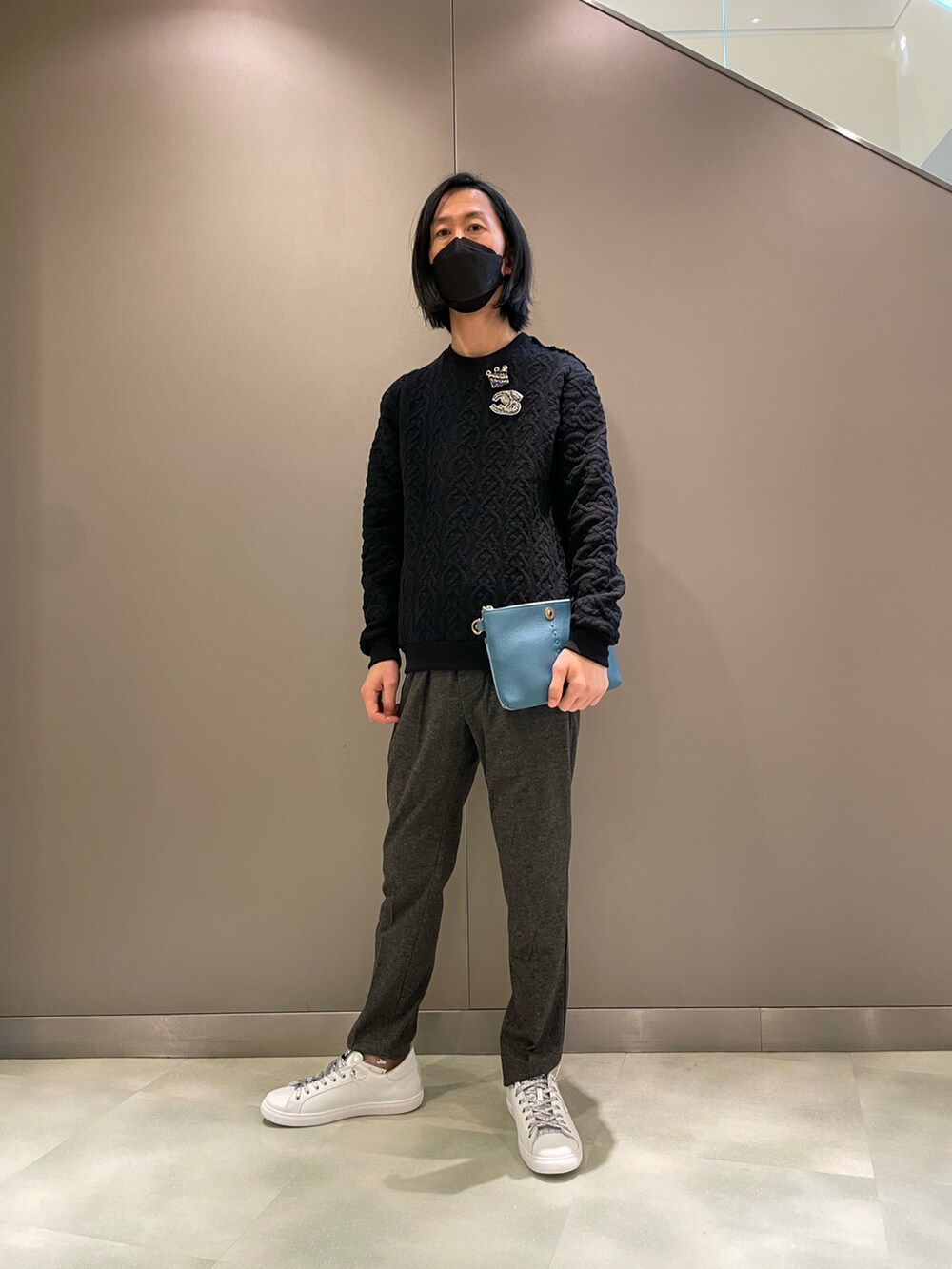 ブラック系のニット/セーター、オレンジ系のボディバッグ/ウエストポーチ、ホワイト系のスニーカーを着用したメンズの秋コーディネートの4枚目の写真