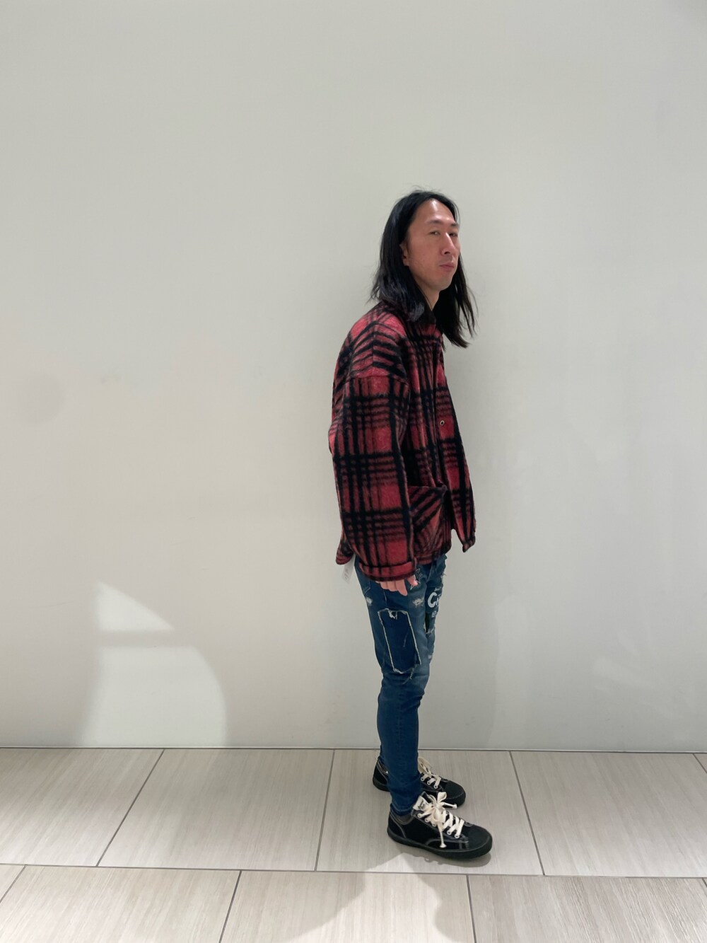 レッド系のシャツ/ブラウス、ブルー系のデニムパンツ、ブラック系のスニーカーを着用したメンズの秋コーディネートの4枚目の写真