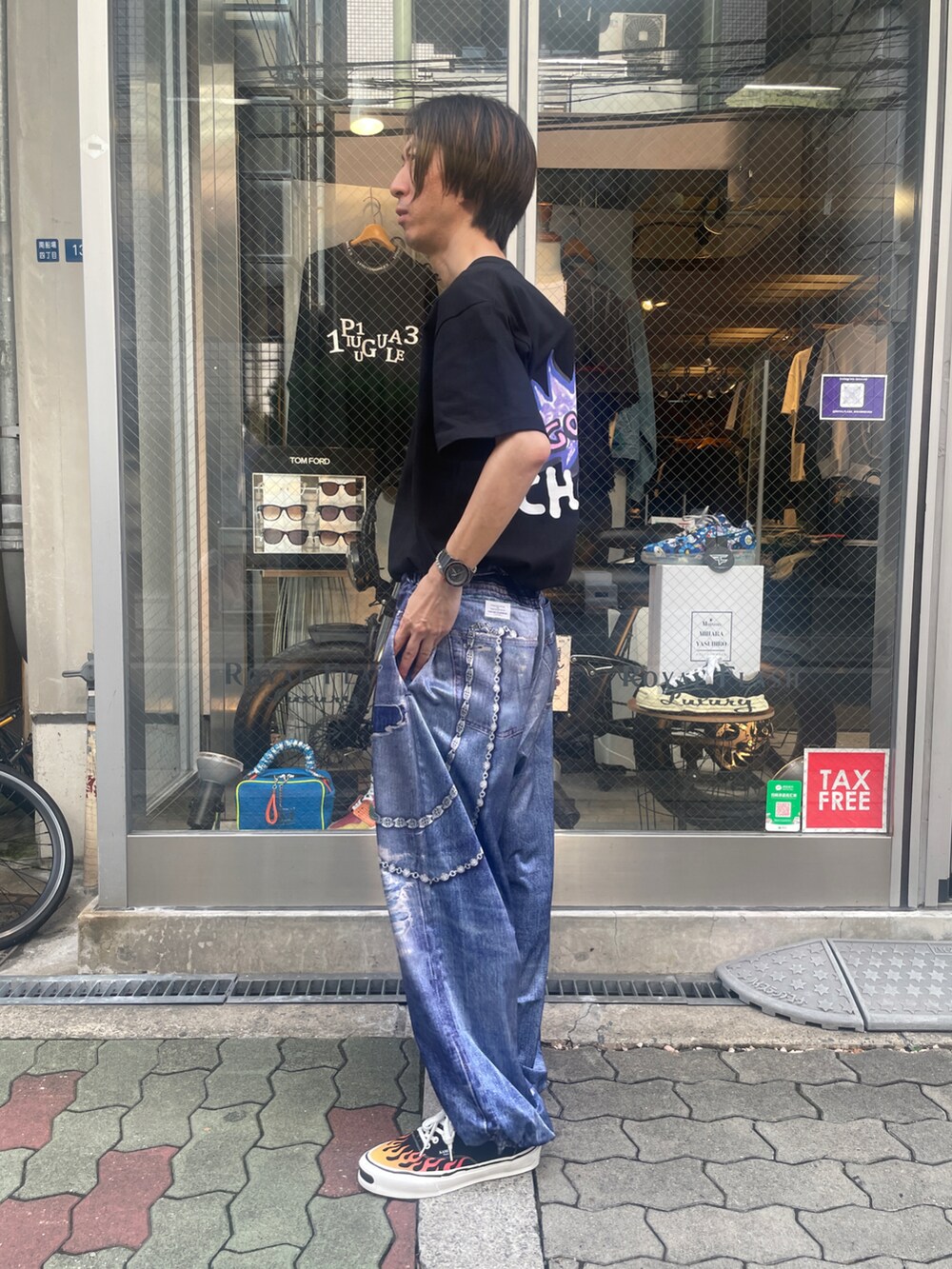 ブラック系のTシャツ/カットソー、ブルー系のパンツ、ブラック系のスニーカーを着用したメンズの夏コーディネートの2枚目の写真