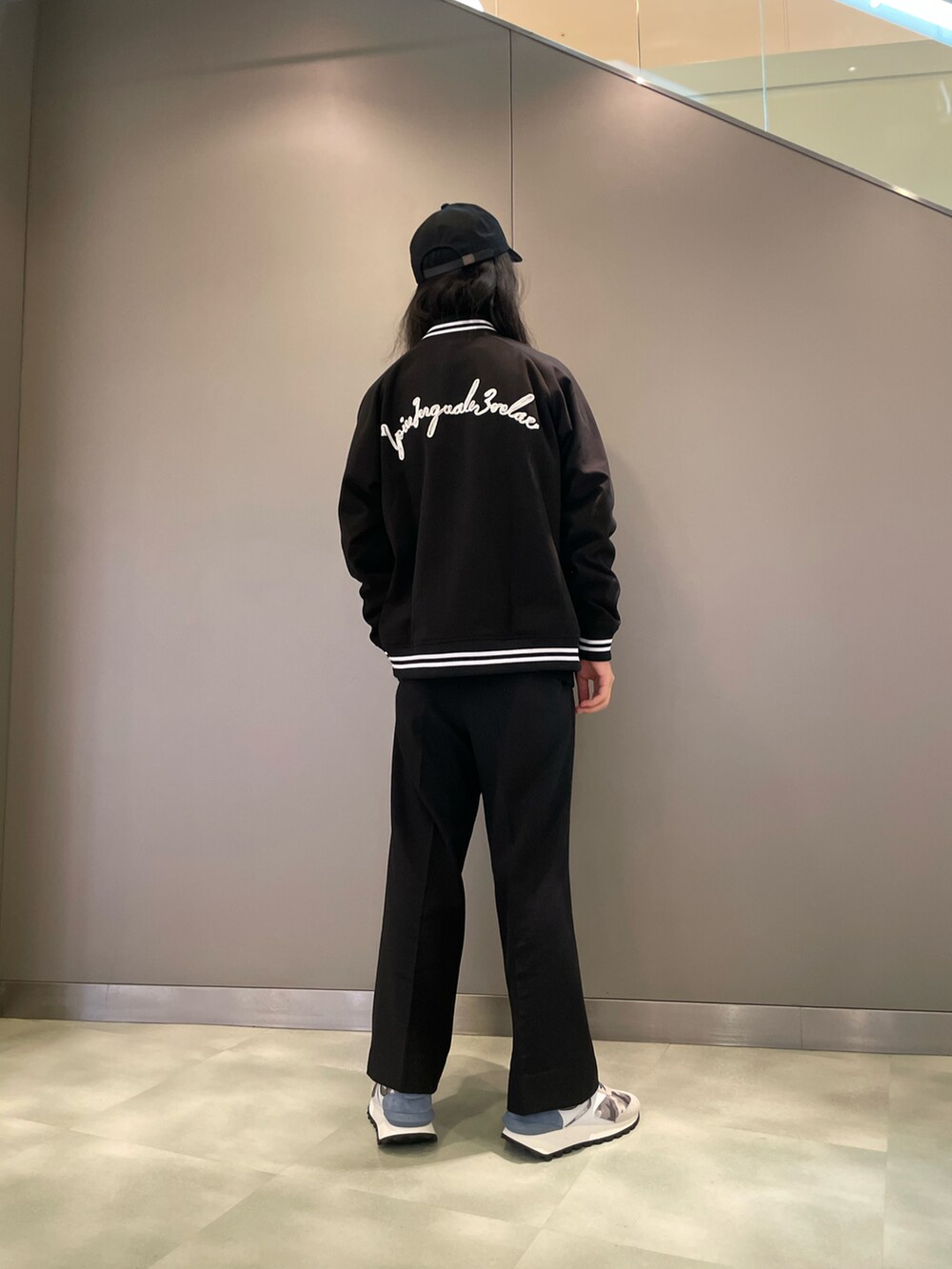 ホワイト系のニット/セーター、ブラック系のスタジャン、グレー系のスニーカーを着用したメンズの秋コーディネートの2枚目の写真