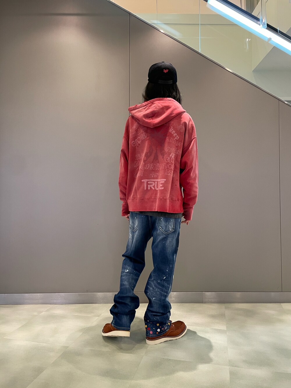 レッド系のトップス、ブルー系のデニムパンツ、ブラウン系のブーツを着用したメンズの秋コーディネートの2枚目の写真