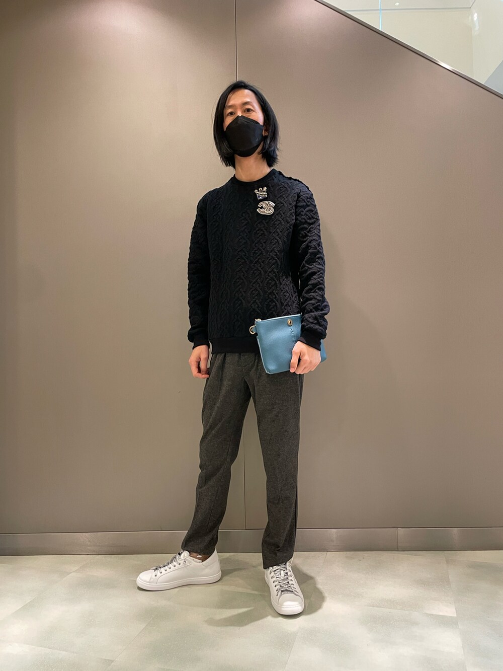 ブラック系のニット/セーター、オレンジ系のボディバッグ/ウエストポーチ、ホワイト系のスニーカーを着用したメンズの秋コーディネートの2枚目の写真