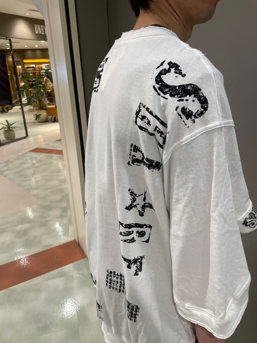 ホワイト系のTシャツ/カットソー、ブラック系のパンツ、ブラック系のスニーカーを着用したメンズの春コーディネートの5枚目の写真