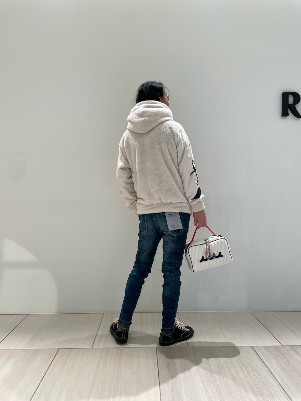 ホワイト系のパーカー、ホワイト系のバッグ、ブルー系のデニムパンツを着用したメンズの秋コーディネートの2枚目の写真