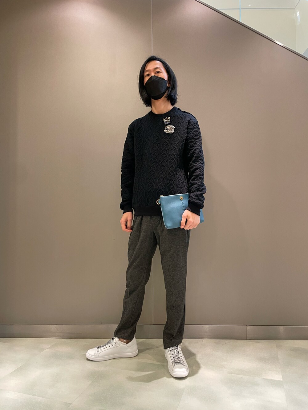 ブラック系のニット/セーター、オレンジ系のボディバッグ/ウエストポーチ、ホワイト系のスニーカーを着用したメンズの秋コーディネートの3枚目の写真