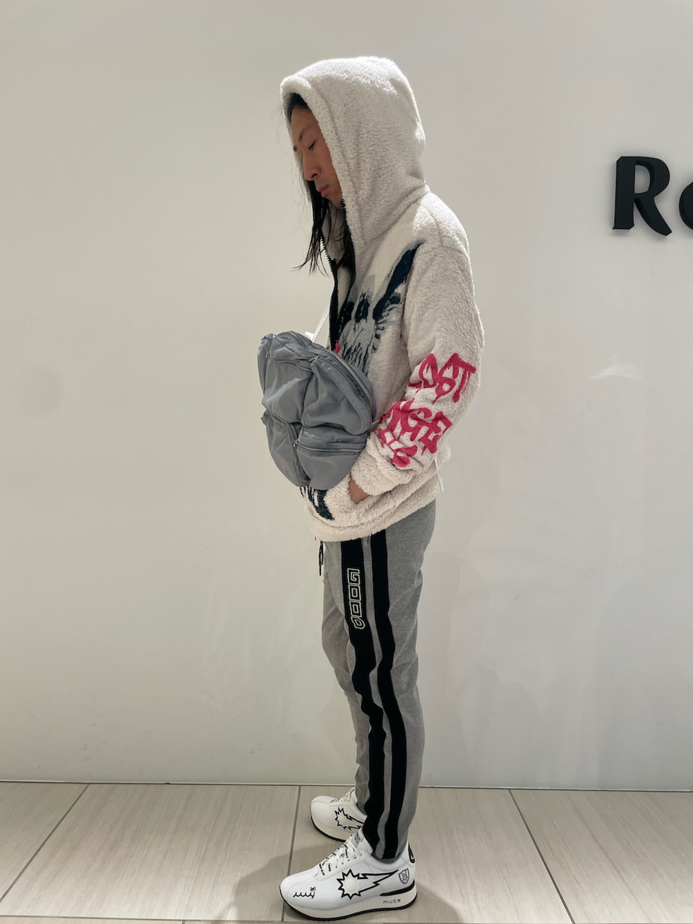 ホワイト系のトップス、ブラック系のショルダーバッグ、ホワイト系のスニーカーを着用したメンズの冬コーディネートの2枚目の写真