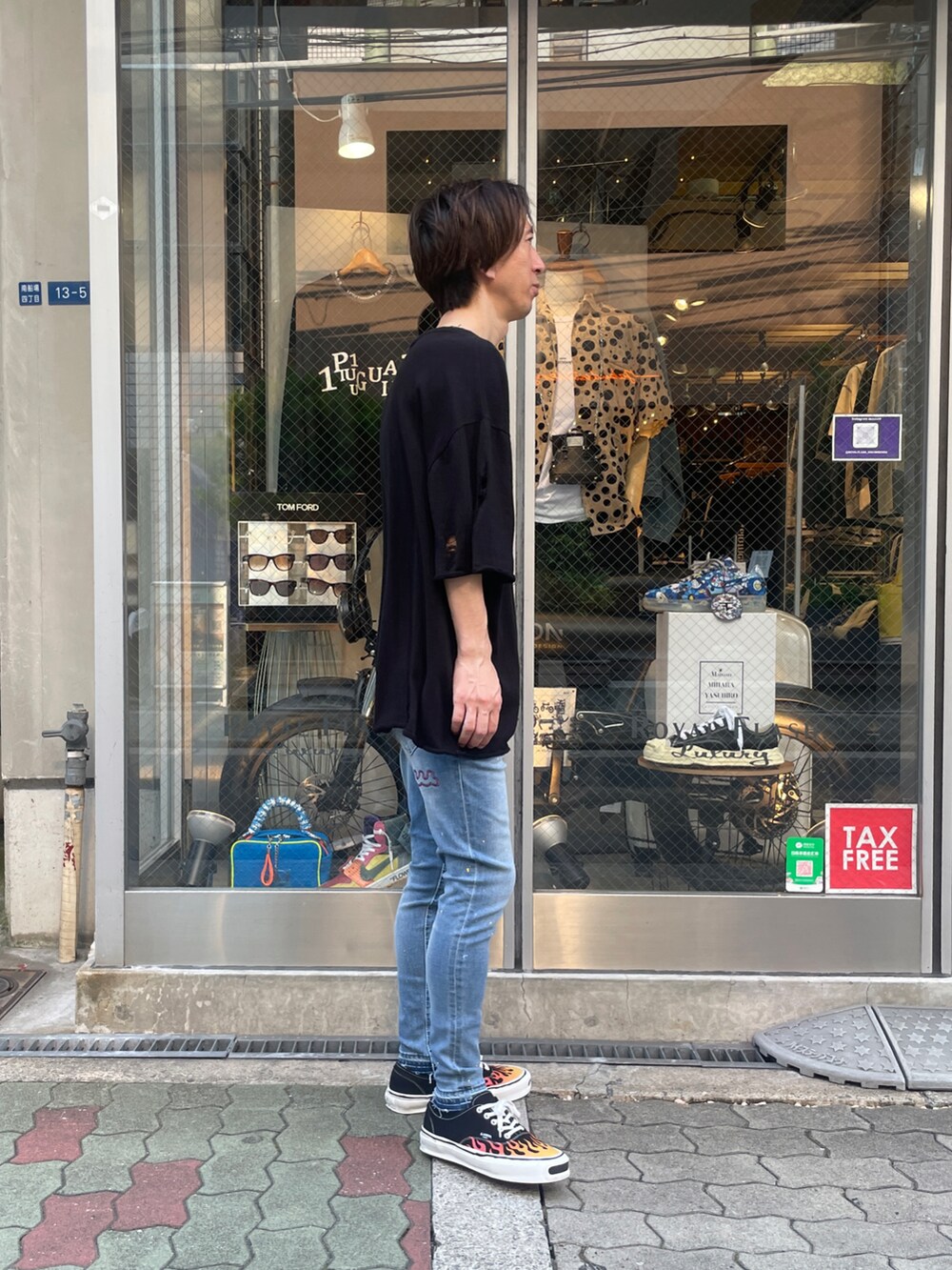 ブラック系のニット/セーター、ブラック系のスニーカー、ブルー系のデニムパンツを着用したメンズの夏コーディネートの2枚目の写真