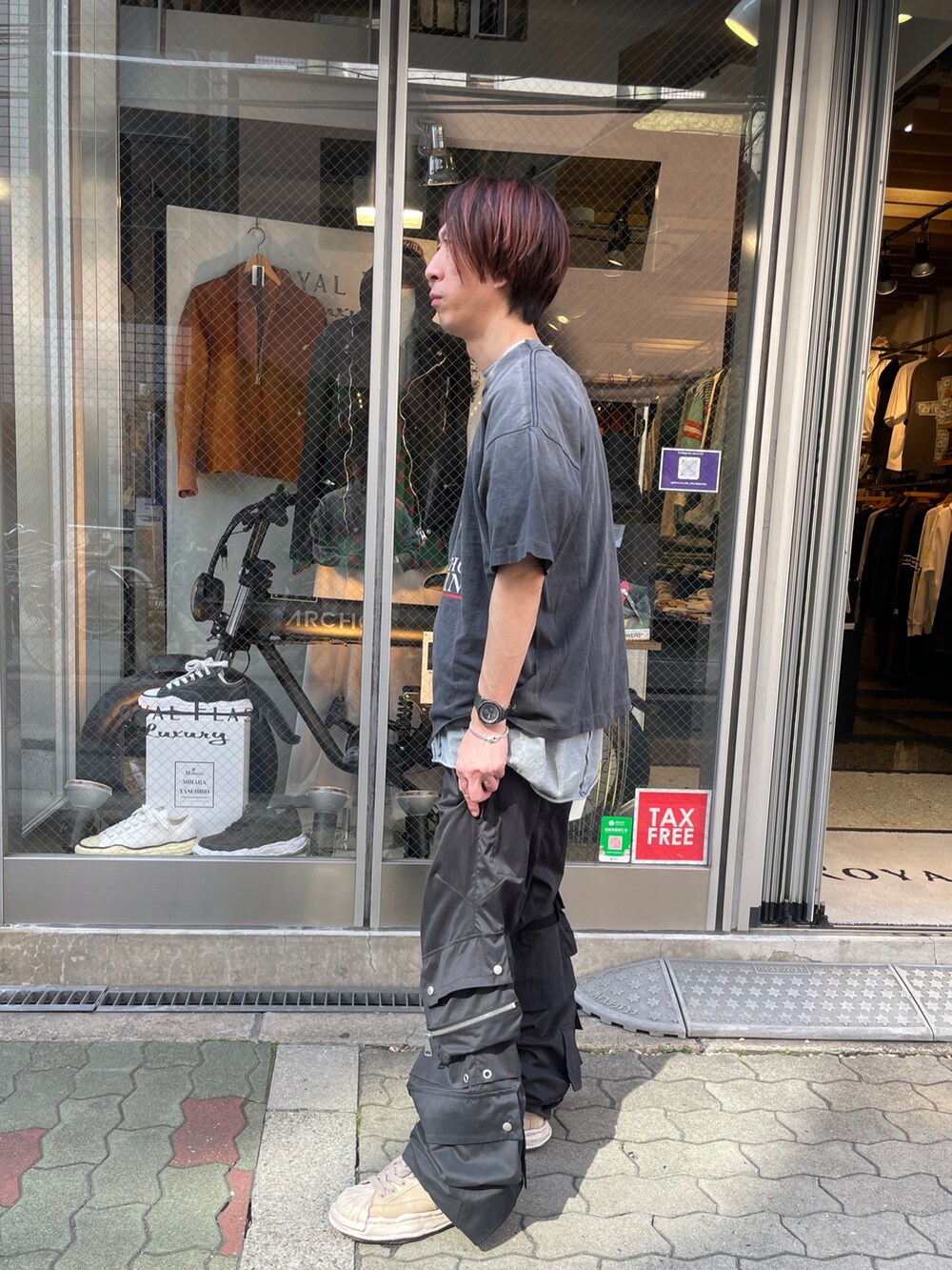 ブラック系のTシャツ/カットソー、ブラック系のカーゴパンツ、ホワイト系のスニーカーを着用したメンズの春コーディネートの3枚目の写真