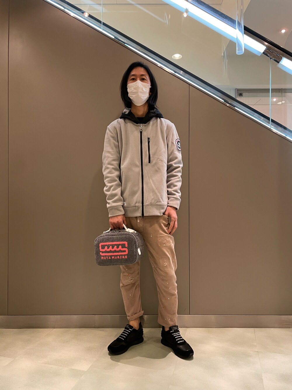 グレー系のブルゾン、グレー系のショルダーバッグ、ベージュ系のデニムパンツを着用したメンズの秋コーディネートの2枚目の写真