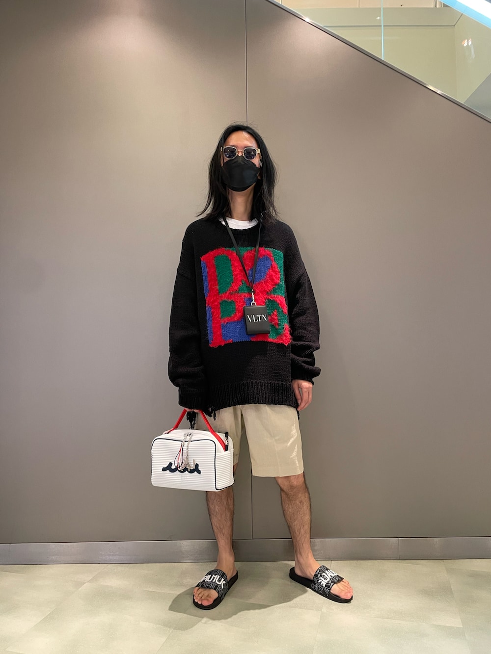 ブラック系のニット/セーター、ホワイト系のバッグ、ベージュ系のパンツを着用したメンズの夏コーディネートの2枚目の写真