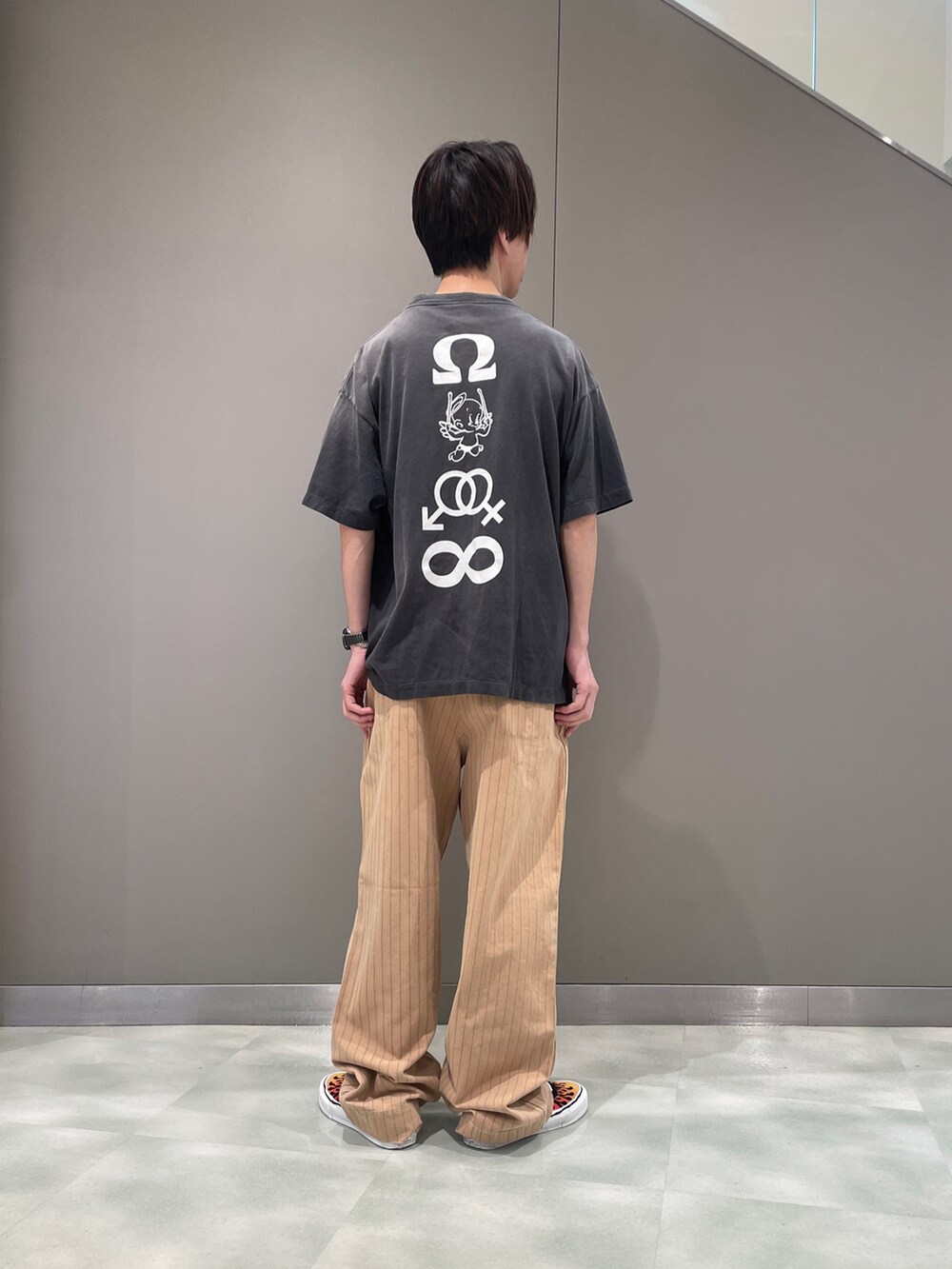 ブラック系のTシャツ/カットソー、ベージュ系のパンツ、ブラック系のスニーカーを着用したメンズの夏コーディネートの2枚目の写真