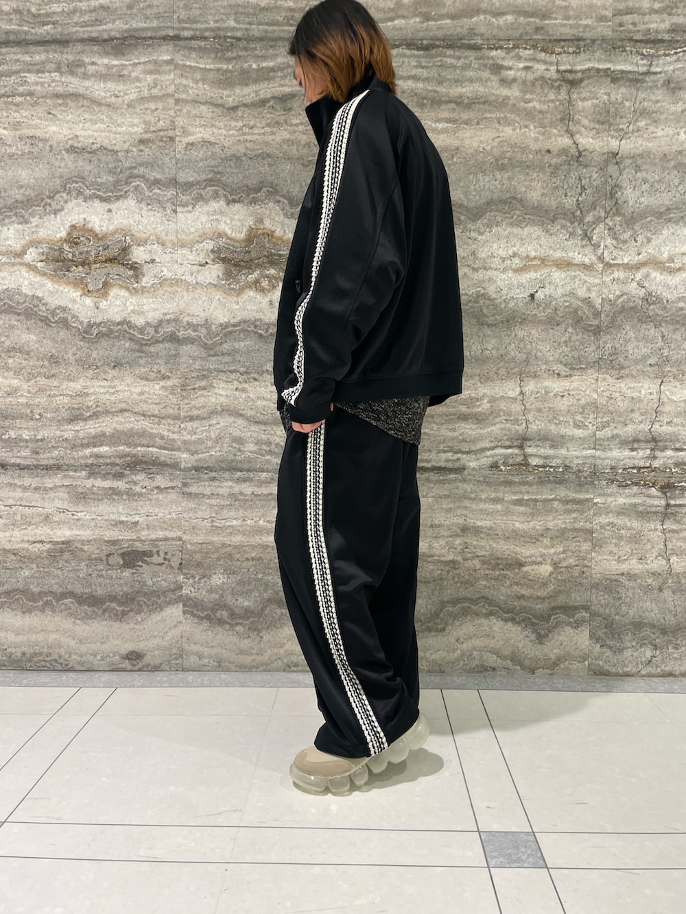 グレー系のニット/セーター、ブラック系のジャージ、ブラック系のパンツを着用したメンズの秋コーディネートの2枚目の写真