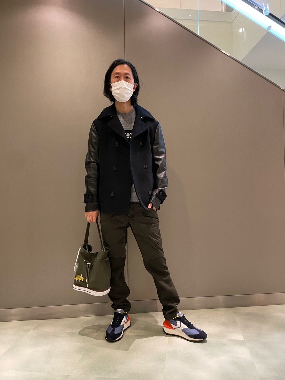 ブラック系のピーコート、グレー系のトップス、ブラック系のショルダーバッグを着用したメンズの秋コーディネートの3枚目の写真