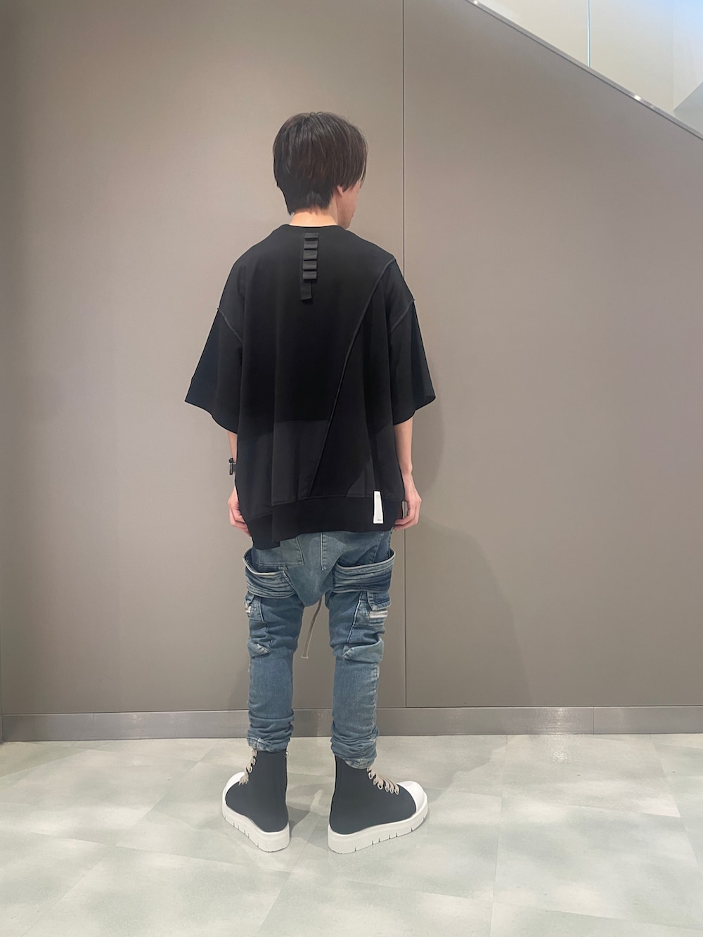 ブラック系のTシャツ/カットソー、ブルー系のデニムパンツ、ブラック系のブーツを着用したメンズの夏コーディネートの3枚目の写真