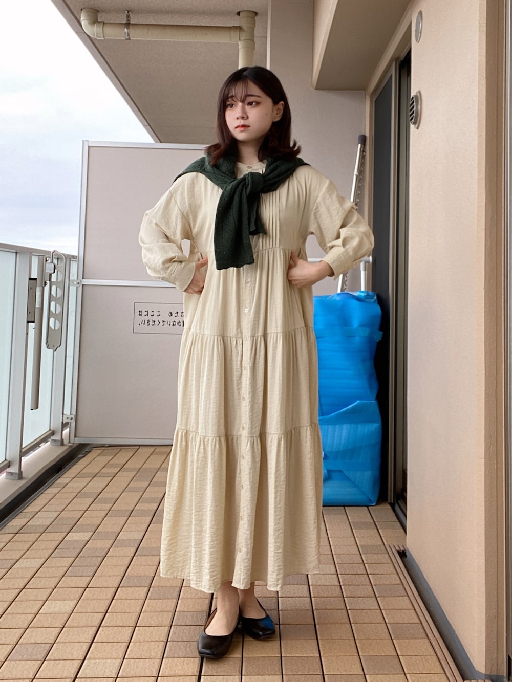 ベージュ系のシャツワンピース、グリーン系のニット/セーター、ブラック系のパンプスを着用したレディースの春コーディネートの2枚目の写真