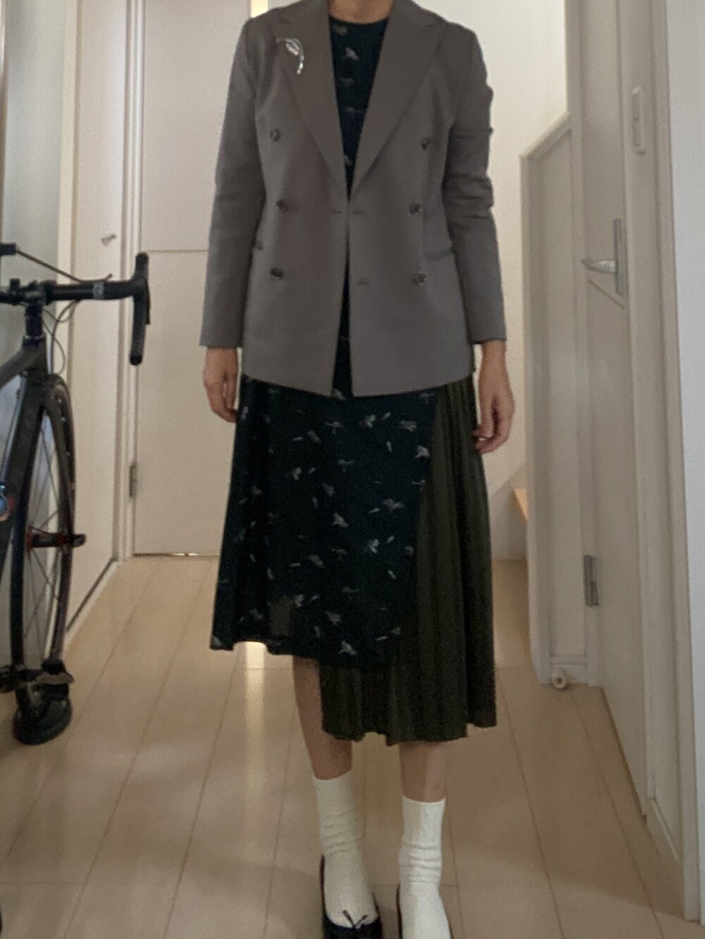 グレー系のテーラードジャケット、グリーン系のワンピースを着用したレディースの冬コーディネートの2枚目の写真