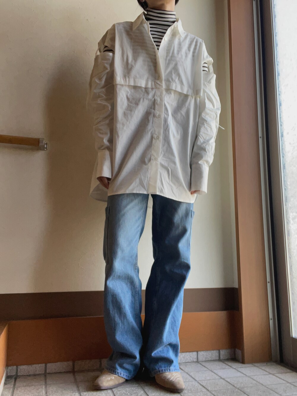 ホワイト系のシャツ/ブラウス、ホワイト系のニット/セーター、ブルー系のデニムパンツを着用したレディースの冬コーディネートの2枚目の写真