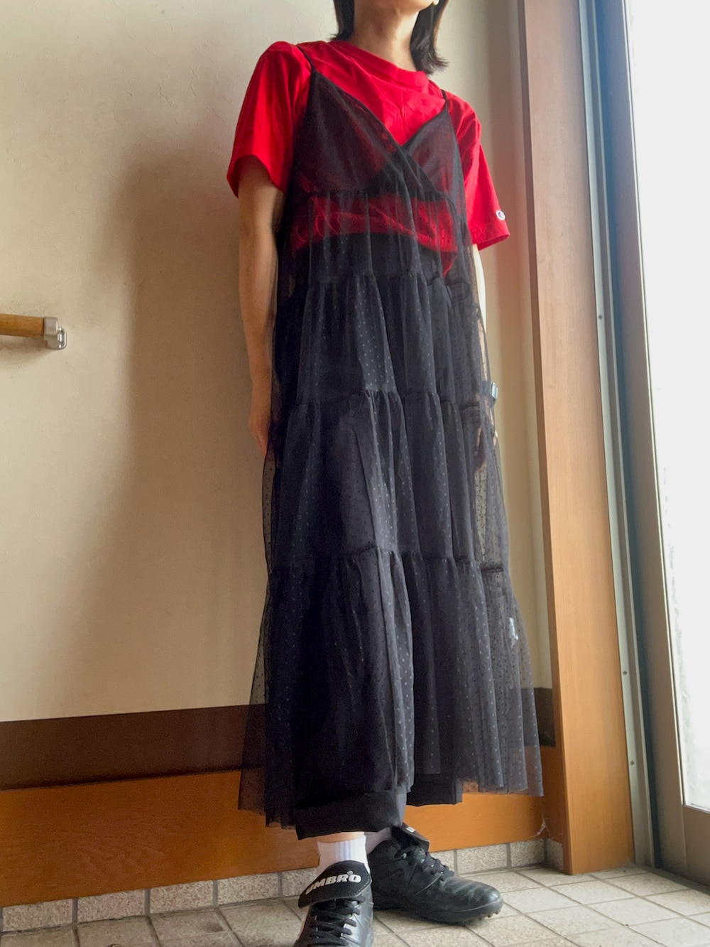 レッド系のTシャツ/カットソー、ブラック系のスニーカー、ブラック系のワンピース/ドレスを着用したレディースの春コーディネートの2枚目の写真