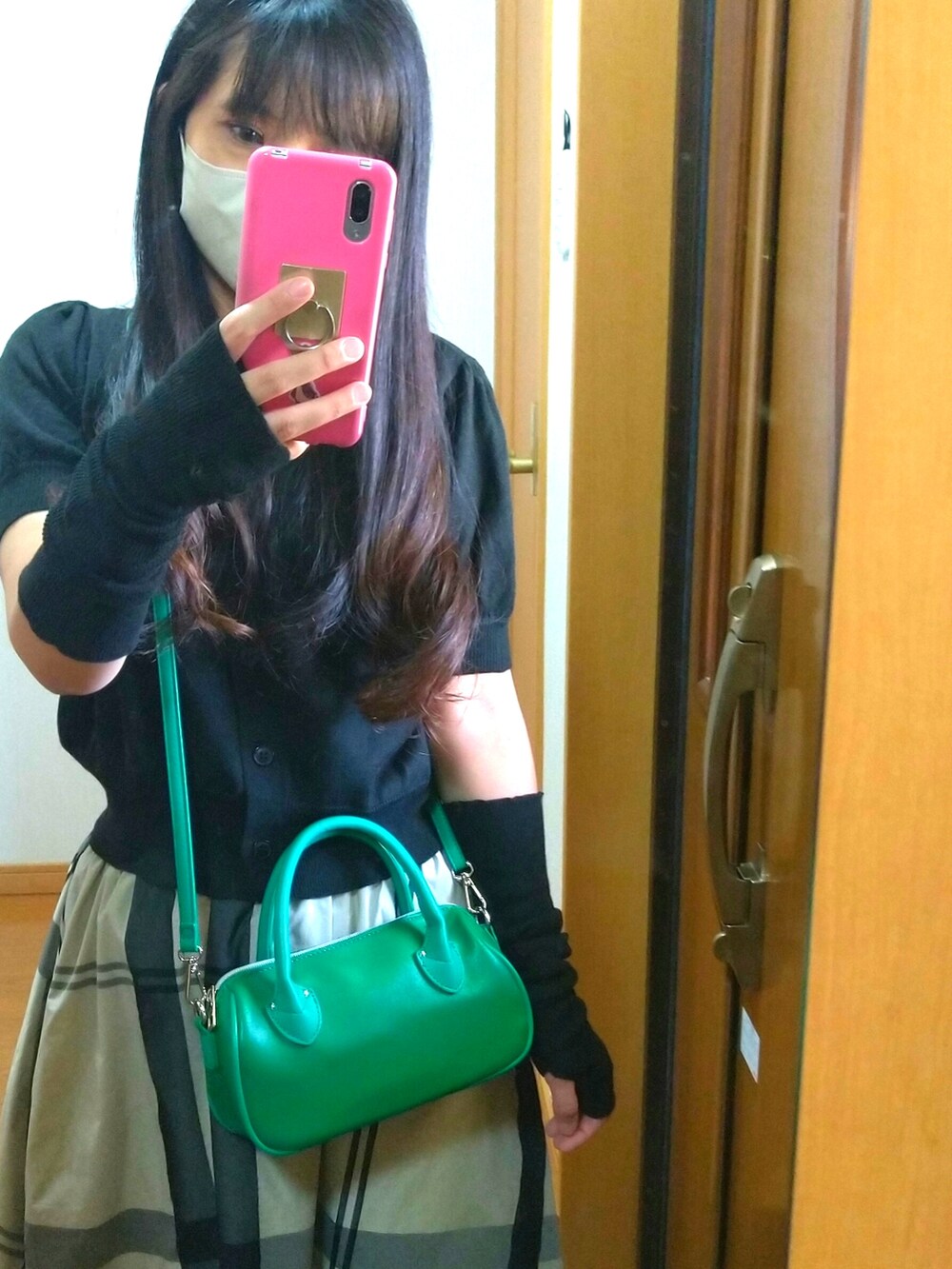 ブラック系のスニーカー、ブラック系のスカート、グリーン系のショルダーバッグを着用したレディースの秋コーディネートの3枚目の写真